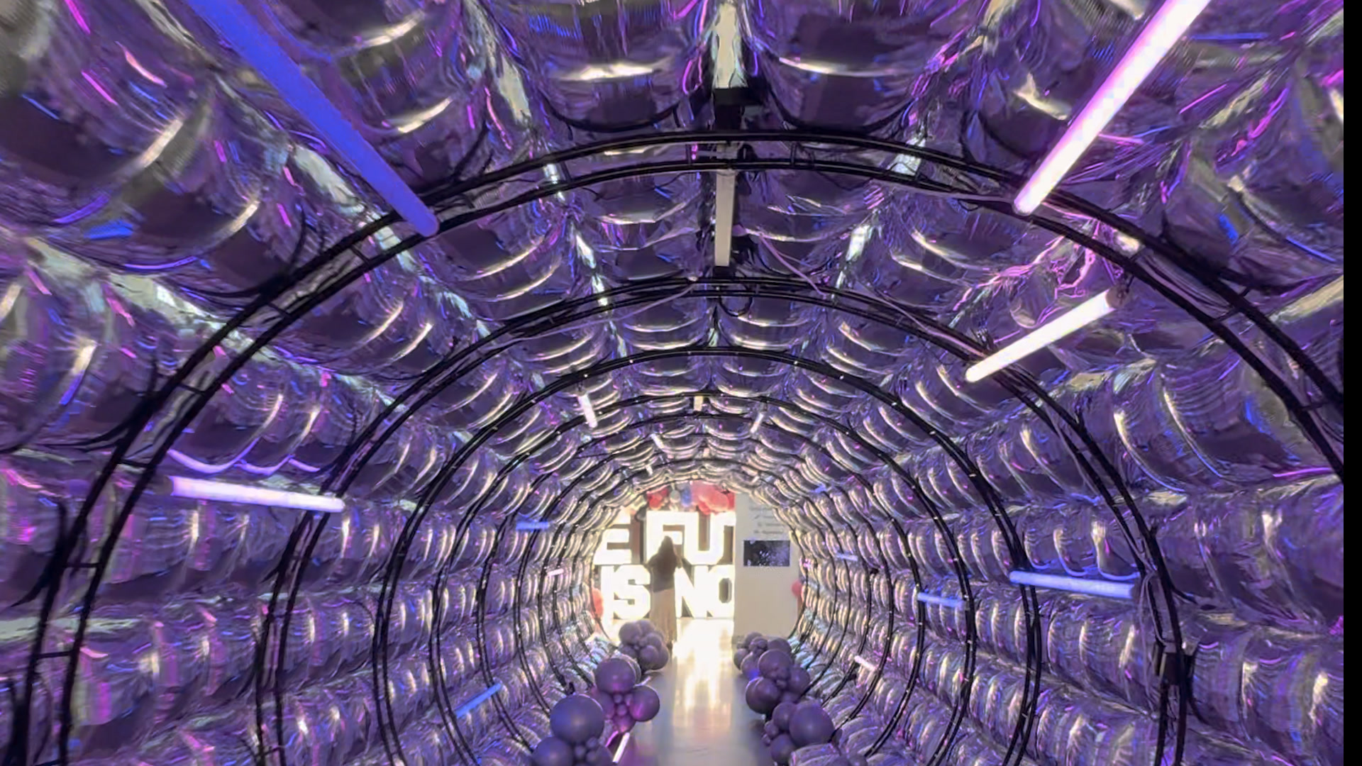 The 40-foot entrance tunnel from the door, overhead tubes racing a purple chase along the balloon arch