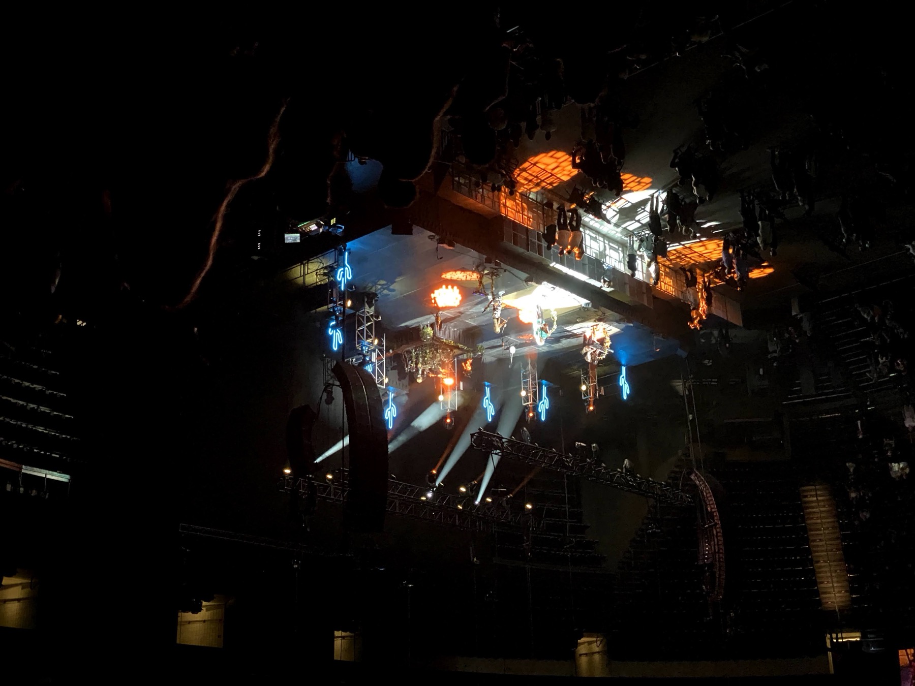 Low, close view looking up at rows of neon cactus fixtures and truss-mounted moving-head lights above a stage