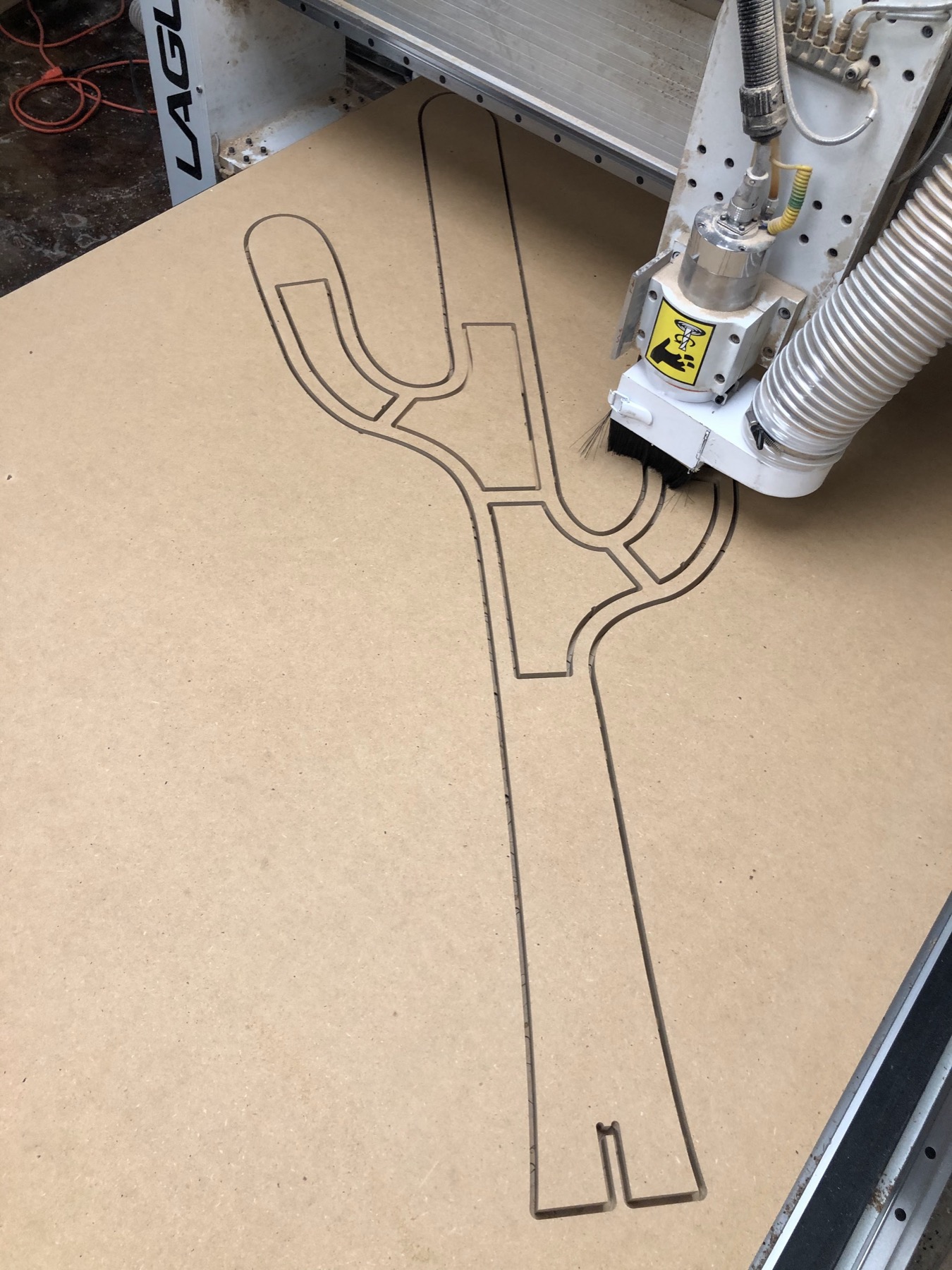The CNC router mid-cut, following the cactus outline in a sheet of MDF