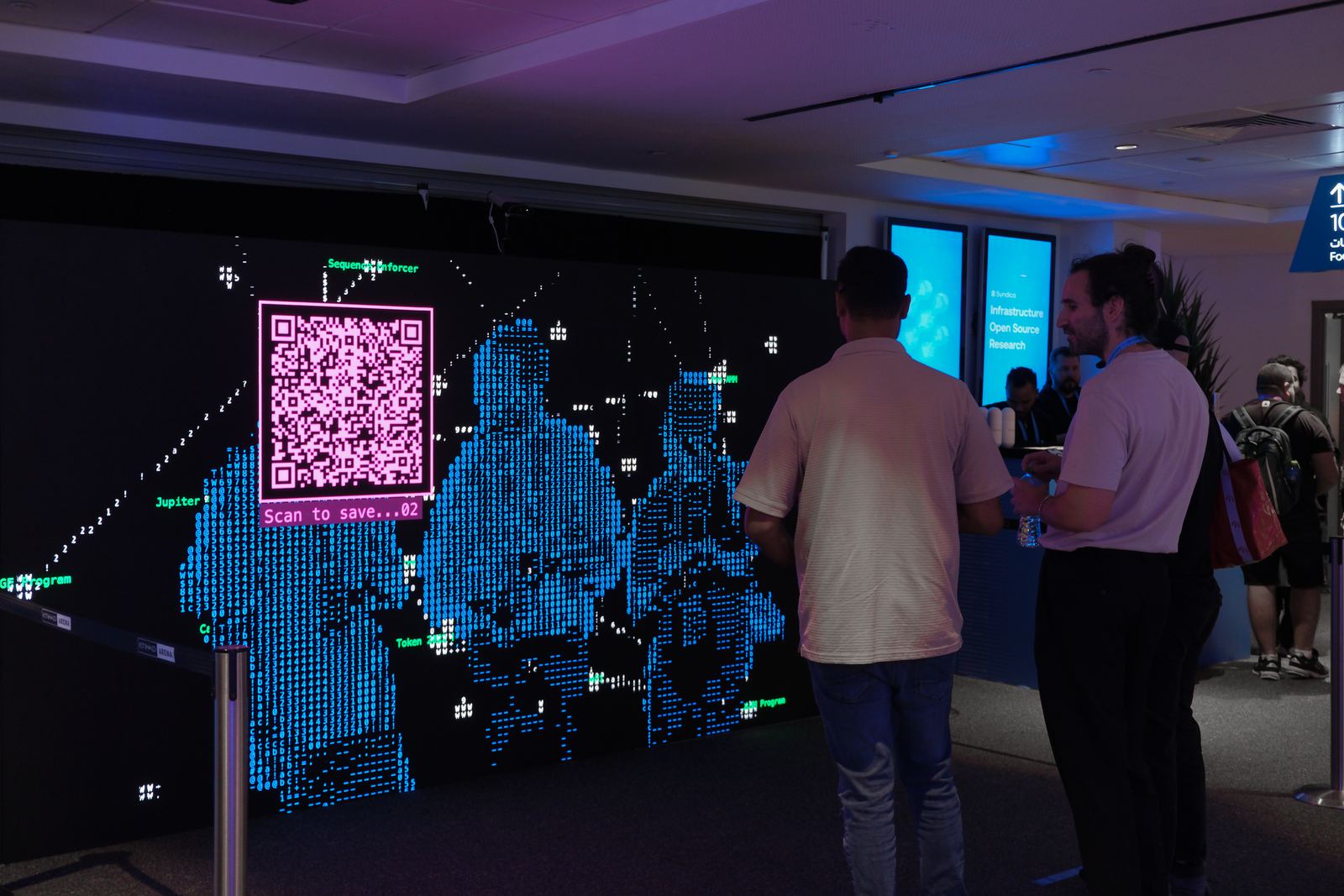 Visitors standing and seated in front of the LED wall, their silhouettes rendered into the visual as a group