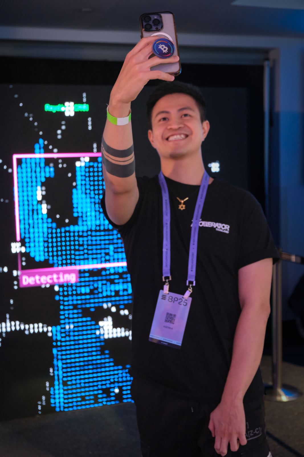 A visitor taking a selfie in front of the wall while being tracked by the installation