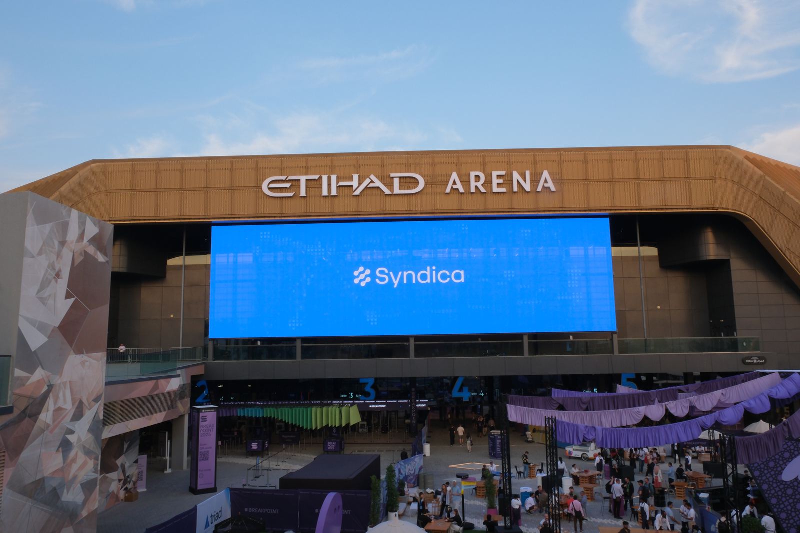 Etihad Arena exterior in Abu Dhabi with Syndica branding on the venue screen