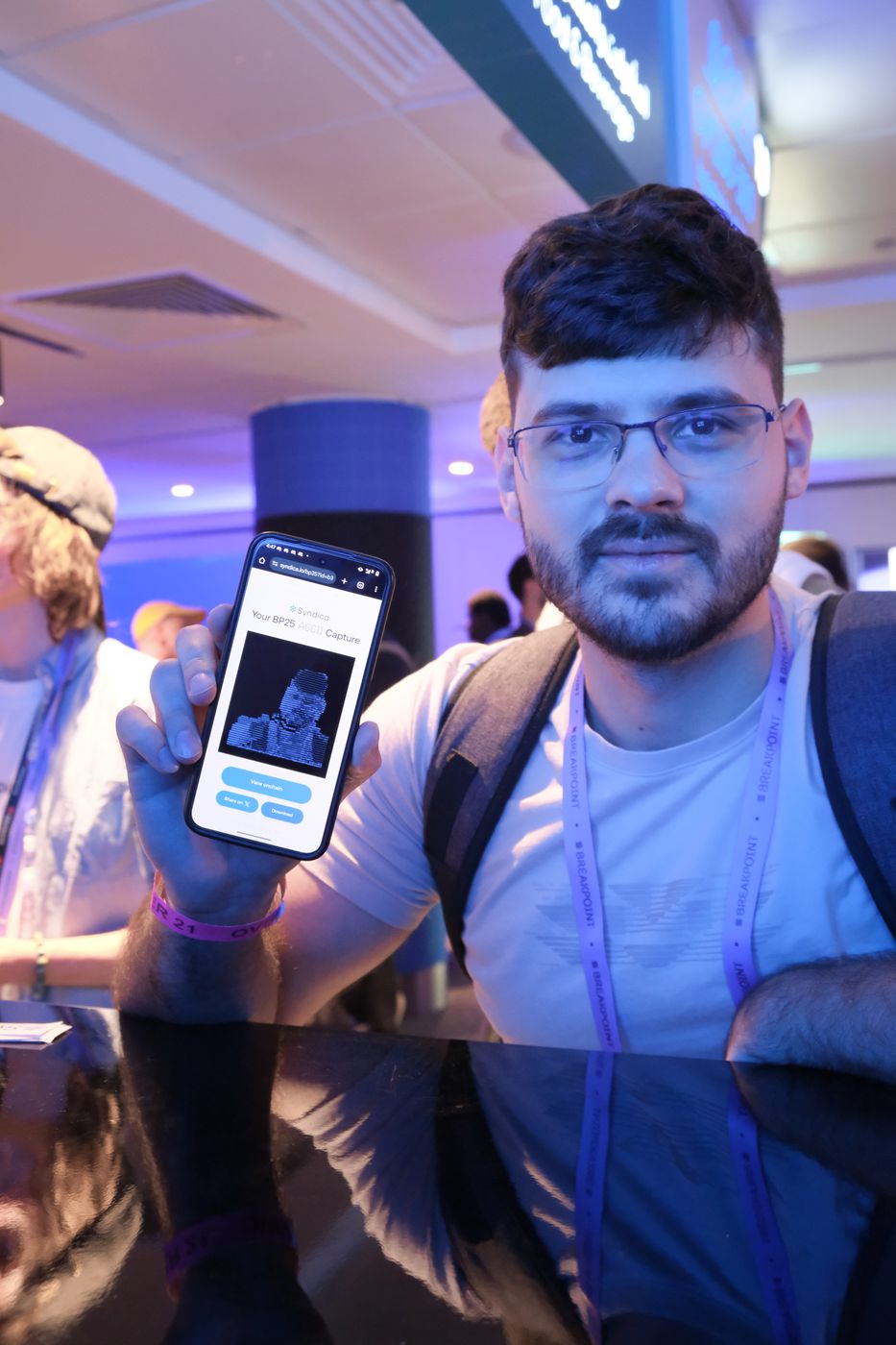 A visitor holding a phone showing their captured ASCII portrait